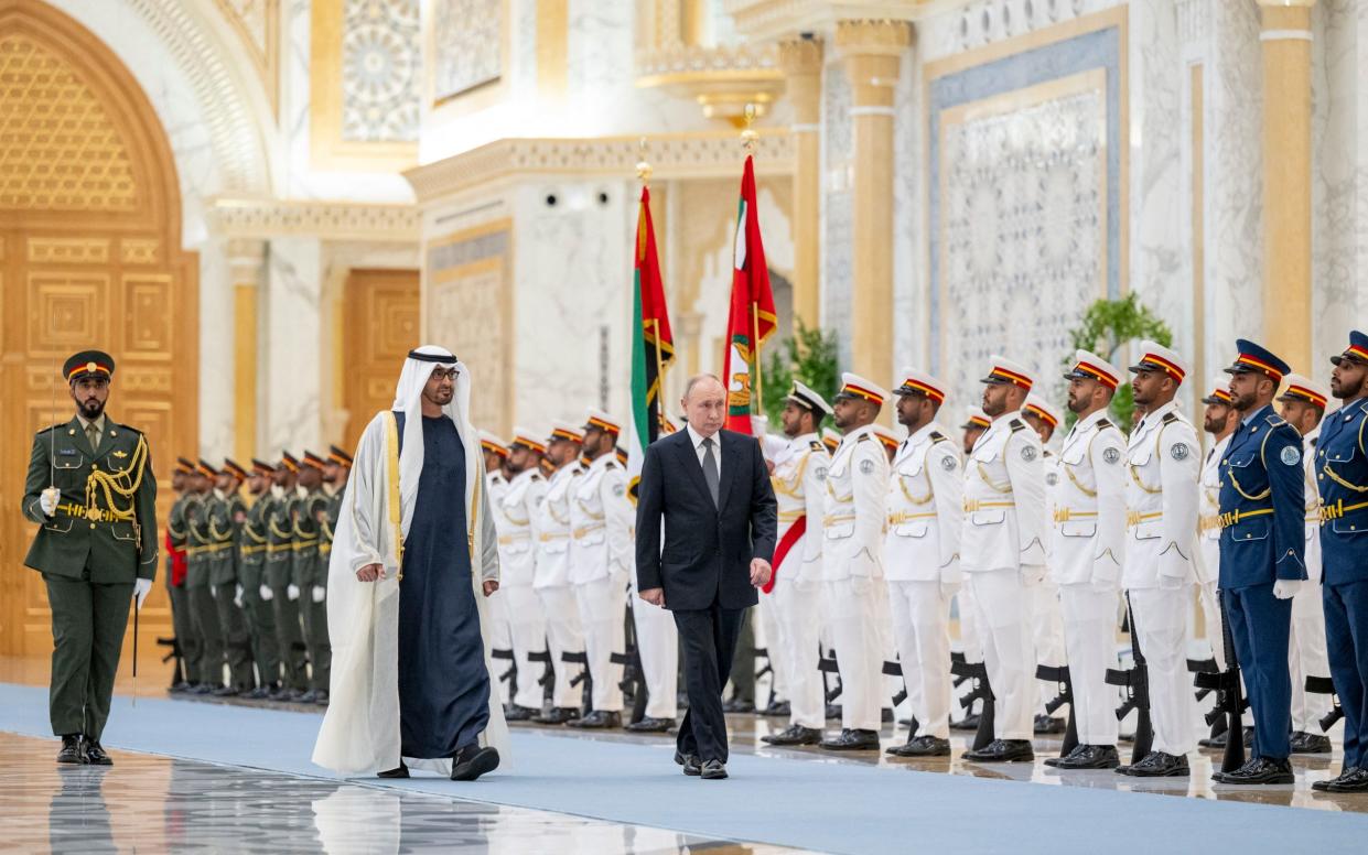 Sheikh Mohamed bin Zayed Al-Nahyan leads Vladimir Putin past a guard of honour at the presidential palace in Abu Dhabi