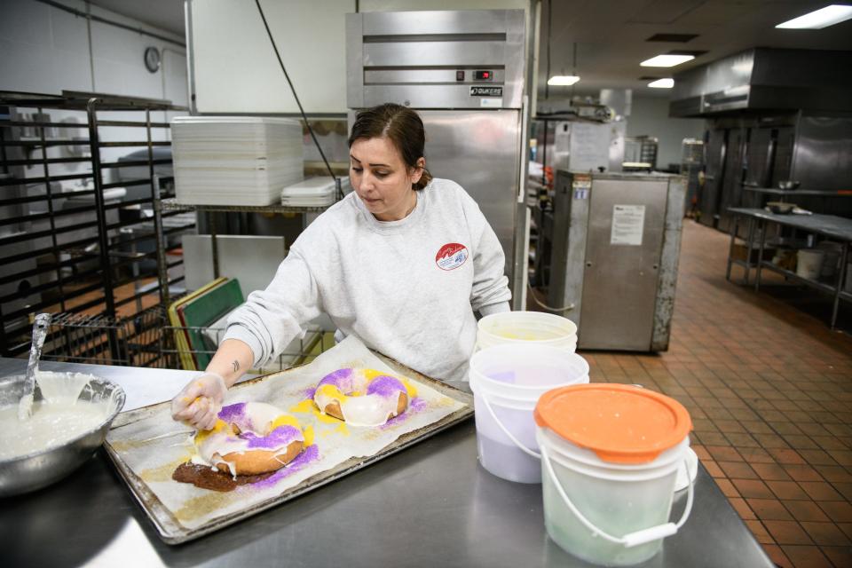 Nadine Ninneman puts the final touches on a couple of king cakes at Superior Bakery on Wednesday, Jan. 26, 2022. The oval-shaped cakes, glazed and decorated with a heavy hand of purple, gold and green dusting sugars to symbolize justice, power and faith, respectively, are traditionally enjoyed during carnival season.