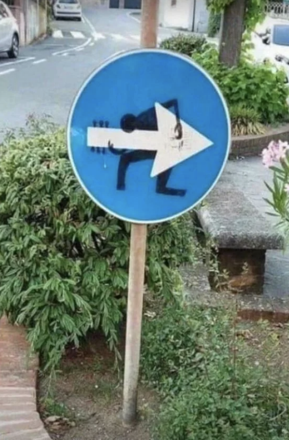 Street sign altered to show a silhouette figure urinating, with an arrow shape integrated