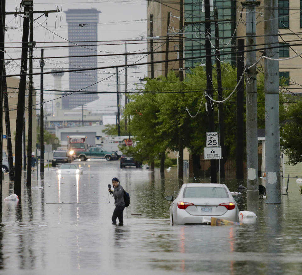 A person crosses a flooded Drexel Drive as heavy rain falls, Wednesday, July 10, 2019, in New Orleans. (David Grunfeld/The Advocate via AP)