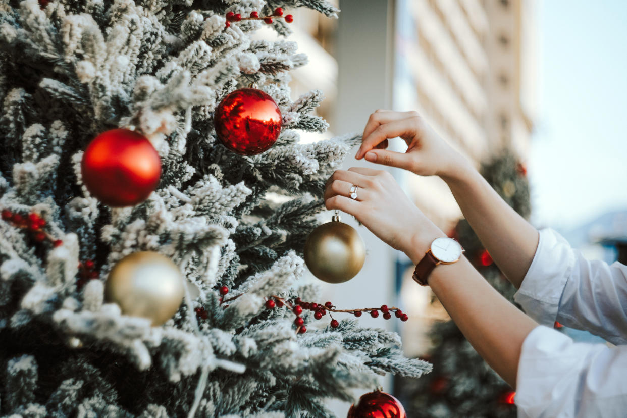 Amazon holiday deals: Cropped hand of woman decorating and hanging baubles on Christmas tree