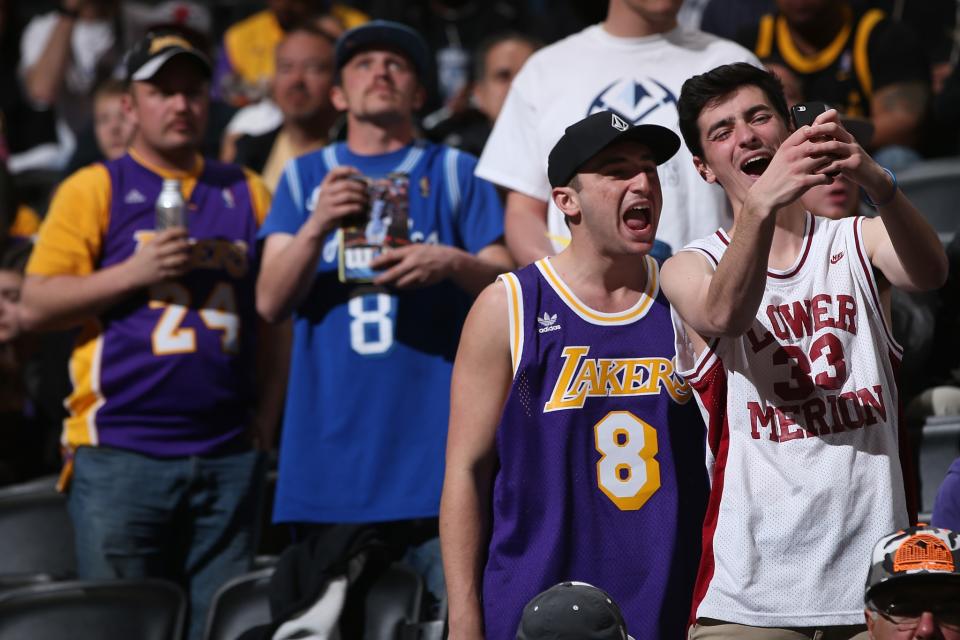 NBA fans look at their phones and, through them, the action on the court. (Getty Images)