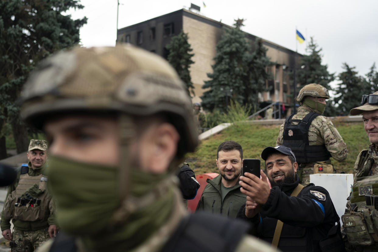 Ukrainian President Volodymyr Zelenskyy poses for a selfie with a police officer after attending a national flag-raising ceremony in the freed Izium, Ukraine, Wednesday, Sept. 14, 2022. Zelenskyy visited the recently liberated city on Wednesday, greeting soldiers and thanking them for their efforts in retaking the area, as the Ukrainian flag was raised in front of the burned-out city hall building. (AP Photo/Leo Correa)