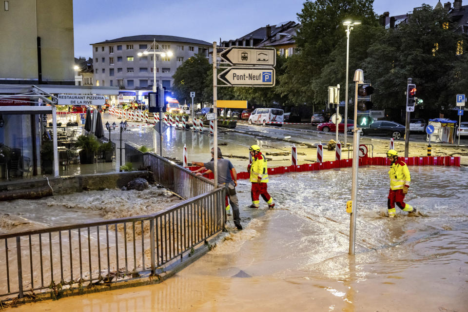 Firefighters look on as the Morges river overflows a road following a storm that caused extensive flooding in the town centre on Tuesday 25 June 2024 in Morges, Switzerland. Clean-up crews and business owners were inspecting the damage Wednesday after sudden storms lashed southwestern Switzerland the previous night, sending torrents of water through roads and temporarily halting air traffic at Geneva's airport. In the lakeside town of Morges, a creek overflowed, inundating downtown streets with tan-colored floodwater.(KEYSTONE/Laurent Gillieron)/Keystone via AP)