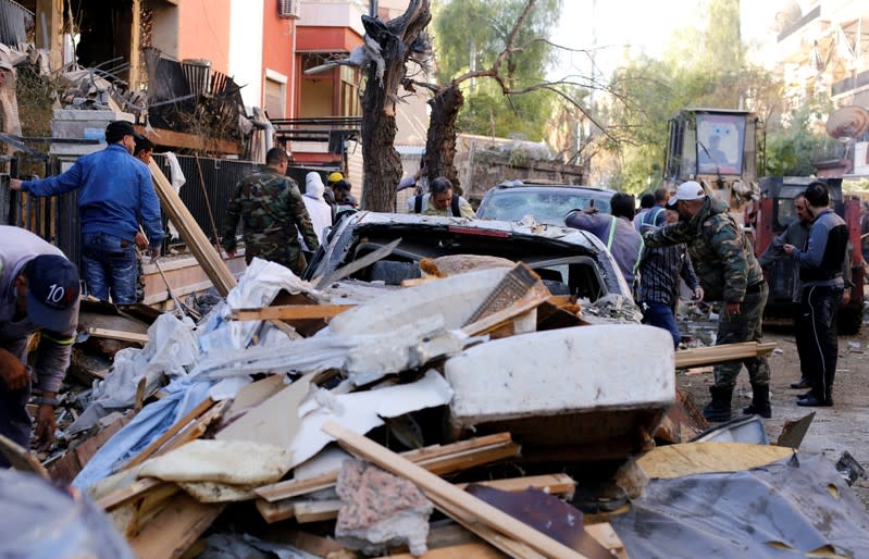 Men and Syrian soldiers gather in front of a damaged building in Mezzah