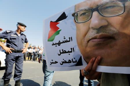 A Jordanian police officer stands guard next a picture of Jordanian writer Nahed Hatter, who was shot dead, during a sit-in in front of the prime minister's building in Amman, Jordan, September 26, 2016. REUTERS/Muhammad Hamed