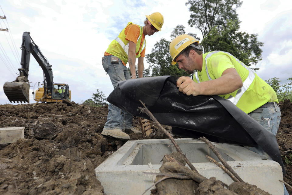 Taylor Purdy, right, a pipe layer with Complete General Construction, and colleague Adam Clary install temporary silt protection for a catch basin near the new Intel semiconductor manufacturing plant construction site in Johnstown, Ohio, Friday, Aug. 5, 2022. Ohio’s largest-ever economic development project comes with a big employment challenge: how to find 7,000 construction workers in an already booming building environment when there's also a national shortage of people working in the trades. (AP Photo/Paul Vernon)