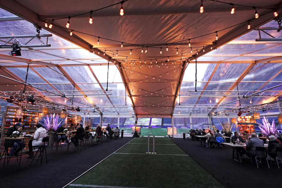 People eat dinner in an outdoor dining tent set up at Lumen Field, the home of the Seattle Seahawks NFL football team, Thursday, Feb. 18, 2021, in Seattle. The "Field To Table" event was the first night of several weeks of dates that offer four-course meals cooked by local chefs and served on the field at tables socially distanced as a precaution against the COVID-19 pandemic, which has severely limited options for dining out at restaurants in the area. (AP Photo/Ted S. Warren)