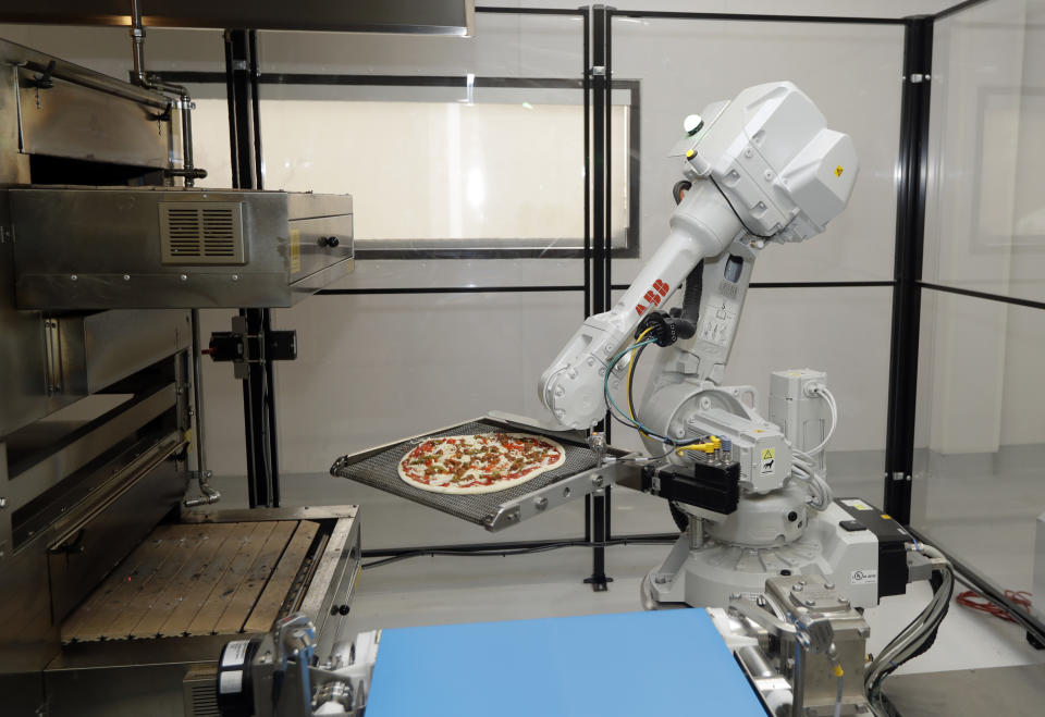 FILE - In this Aug. 29, 2016, file photo, a robot places a pizza into an oven at Zume Pizza in Mountain View, Calif. It has not been a good week for robots in the San Francisco Bay Area. A Silicon Valley company that used robots to make its pizzas closed this week and three coffee shops in downtown San Francisco that used robots as baristas also shuttered. Zume Pizza said it is cutting 172 jobs in Mountain View, and eliminating another 80 jobs at its facility in San Francisco. Zume Chief Executive Alex Garden made the announcement about Zume in an email to company employees on Wednesday, Jan. 8, 2020, the Mercury News reported. (AP Photo/Marcio Jose Sanchez, File)