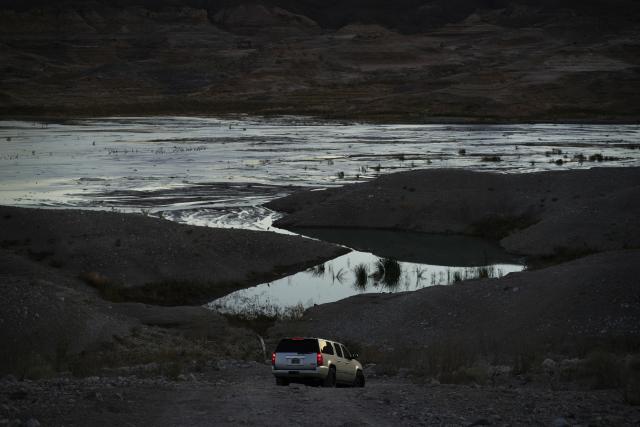 FILE - A car drives along a dirt road near Lake Mead at the Lake Mead National Recreation Area on Jan. 27, 2023, near Boulder City, Nev. Arizona, California and Nevada said on Monday, May 23, 2023, that they have reached an agreement to cut their use of the Colorado River in exchange for federal money. (AP Photo/John Locher, File)
