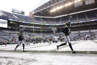 Seattle Seahawks players run on a partially snow-cleared field before an NFL football game against the Chicago Bears, Sunday, Dec. 26, 2021, in Seattle. Snow blanketed parts of the Pacific Northwest on Sunday because of unusually cold temperatures in the region. Between 3 and 5 inches of snow fell in Seattle overnight and frigid temperatures in the region could tie or break records in the coming days. (AP Photo/Lindsey Wasson)