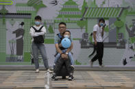 A man holds a child wearing a mask to curb the spread of the coronavirus as they watch a water fountain on Children's Day in Beijing on Monday, June 1, 2020. (AP Photo/Ng Han Guan)