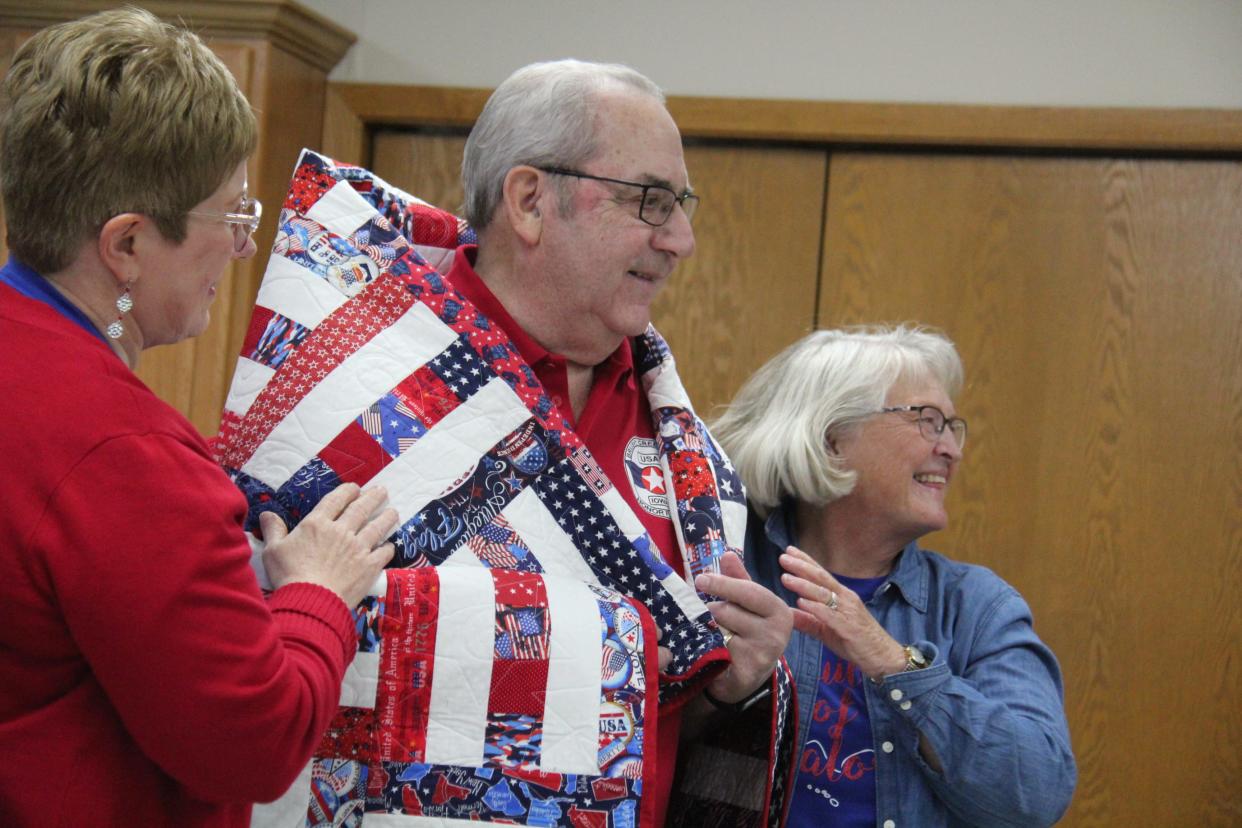 Members of the Perry Piecemakers help wrap John "Jack" Lint in a Quilt of Valor during a presentation on on Friday, Nov. 10, 2023, at the Perry Elks Lodge.