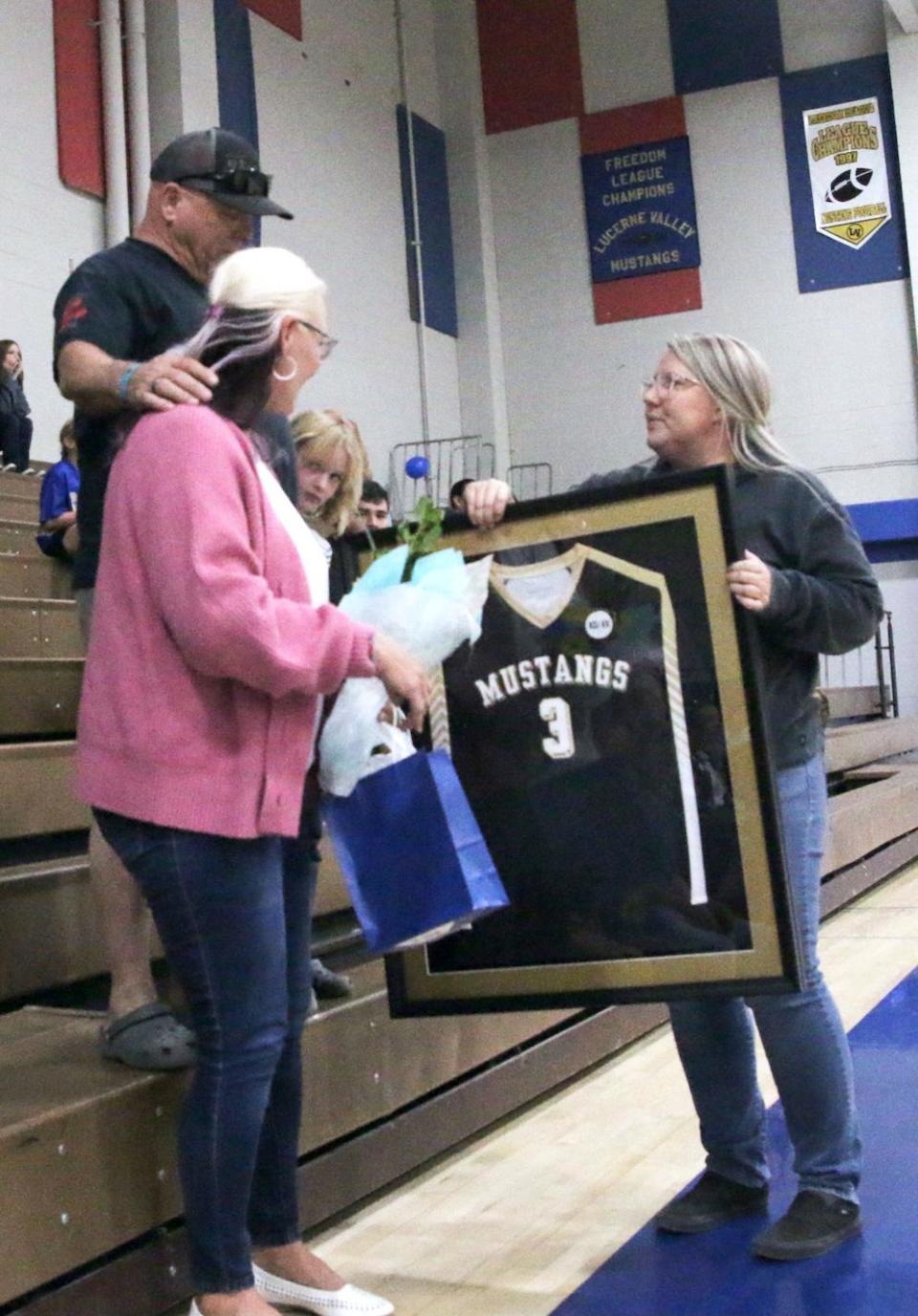 Lucerne Valley High School volleyball coach Amanda Nichols presents the retired jersey of the late-Kristy Klaus,16, to her family during a Lady Mustangs’ volleyball team game on Thursday, Oct. 12, 2023.