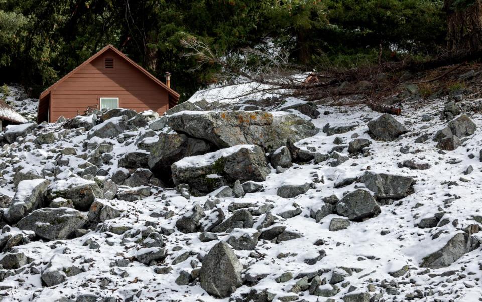 Snow covers a rocky hillside near a small cabin along Mt. Baldy Road