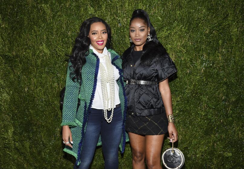 Angela Simmons, left, and Keke Palmer posing together in front of green backdrop.