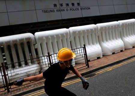 FILE PHOTO: An anti-extradition bill protester throws a stone at a police station in Tseung Kwan O residential district, in Hong Kong