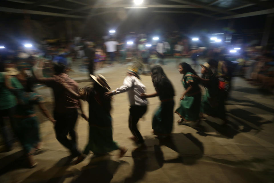 In this Nov. 25, 2018 photo, Ngabe Bugle indigenous people dance during the opening of the second edition of the Panamanian indigenous games in Piriati, Panama. At night, the groups intermingled to share dance and music traditions. (AP Photo/Arnulfo Franco)