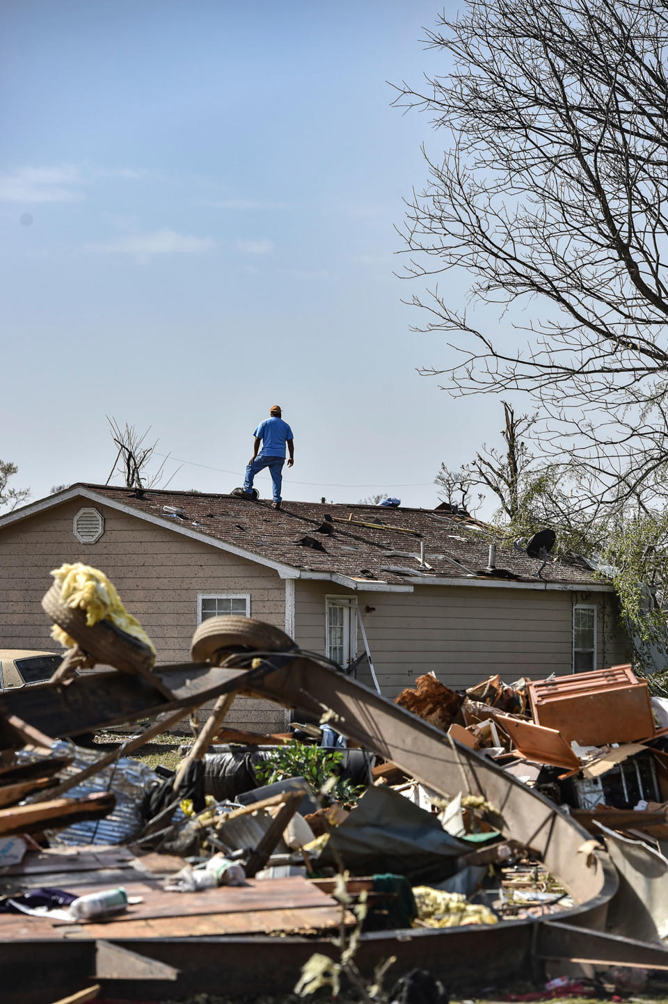 A resident of Silver City, Miss., stands on top of his house on March 25, 2023, to survey the surrounding damage following a deadly tornado that ripped through the state Friday night.<span class="copyright">Hannah Mattix—The Clarion-Ledger/AP</span>