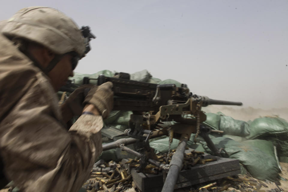 FILE - In this Aug. 25, 2011, file photo, a U.S. Marine fires a heavy machine gun to counter Taliban fire from a nearby tree line in Helmand province, southern Afghanistan. The Marines departed in transport helicopters, their destination classified. Veterans of America's longest war are torn as the U.S. signs a potentially historic peace accord with the Taliban in Afghanistan. For many, the U.S. is overdue in withdrawing its forces after more than 18 years of fighting. Others are wary of the Taliban, whose hard-line government the U.S.-led forces overthrew in 2001. (AP Photo/Brennan Linsley, File)