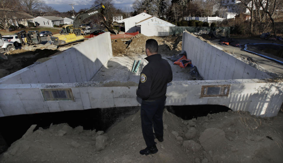 Lawrence, Mass. police officer Ivan Soto looks as contractors work on a new foundation at the former site of his family home, which was destroyed on Sept. 13, 2018 after a gas line explosion in Lawrence, Mass., Friday, Dec. 7. Following a gas line failure, which displaced thousands of Lawrence residents, many residents and business owners are dealing with the after effects of the crisis. Officials announced that most have been connected back to their service following the fires, explosions and loss of their main heating utility, but there are many issues which still need to be solved. (AP Photo/Charles Krupa)