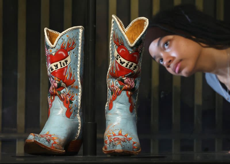 La empleada Saffron posa mientras ve unas botas vaqueras usadas y prestadas por Taylor Swift, que forman parte de la exposición "Taylor Swift I Songbook Trail" que celebra el trabajo de la artista musical en el Museo V&A de Londres, Reino Unido