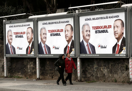 FILE PHOTO: People walk past by AK Party billboards with pictures of Turkish President Tayyip Erdogan and mayoral candidate Binali Yildirim in Istanbul, Turkey, April 1, 2019. The billboards read: " Thank you Istanbul ". REUTERS/Murad Sezer