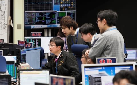 Staff of the Hayabusa2 Project watch monitors for a safety check at the control room of the JAXA Institute of Space and Astronautical Science in Sagamihara, near Tokyo - Credit: AP