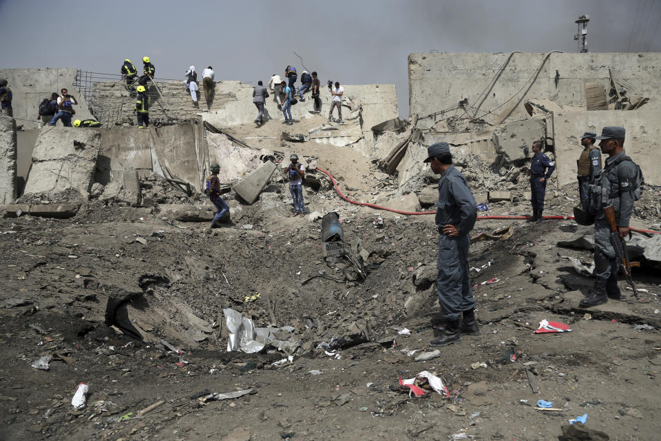 Journalists and security forces stand next to a crater caused by Monday's suicide bomb attack in Kabul, Afghanistan, Tuesday, Sept. 3, 2019. (AP Photo/Rahmat Gul)