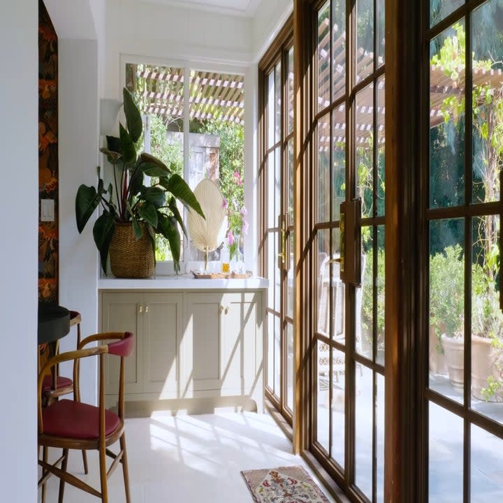 One of the rooms has a table in the corner and there is a glass door and ceiling to floor glass windows