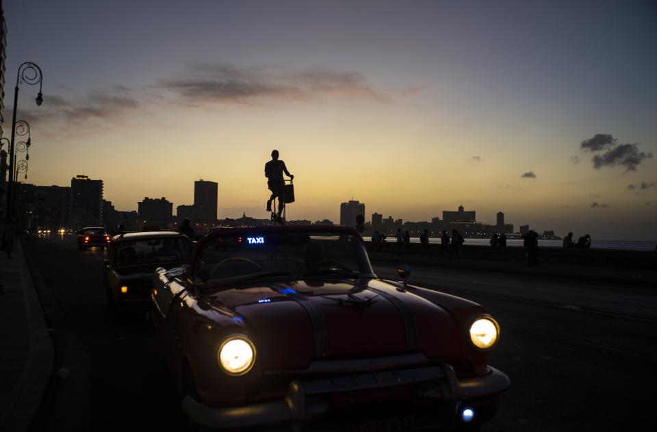 Felix Girola rides his 11-foot tall, custom-made bicycle in Havana, Cuba, Thursday, Feb. 6, 2020. Ever since he was a child, Girola dreamed of riding tall bicycles. For the past 35 years he's been able to live his dream on the streets of Cuba, winding his way, in tall fashion, between pedestrians and classic cars. (AP Photo/Ramon Espinosa)