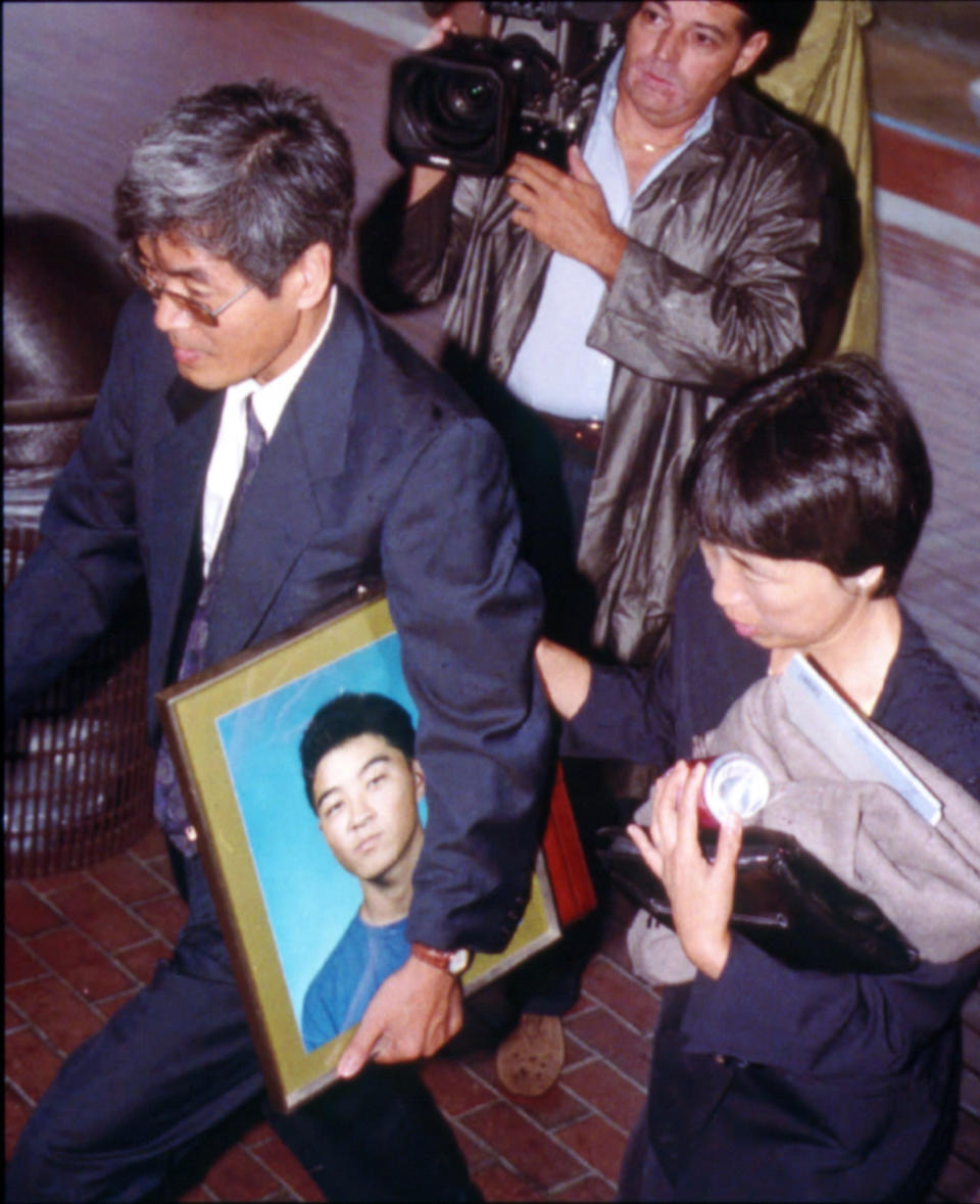 Masaichi and Mieko Hattori enter district court carrying a photo of their slain son, Yoshihiro. Source: AP Photo/Stan Alost.