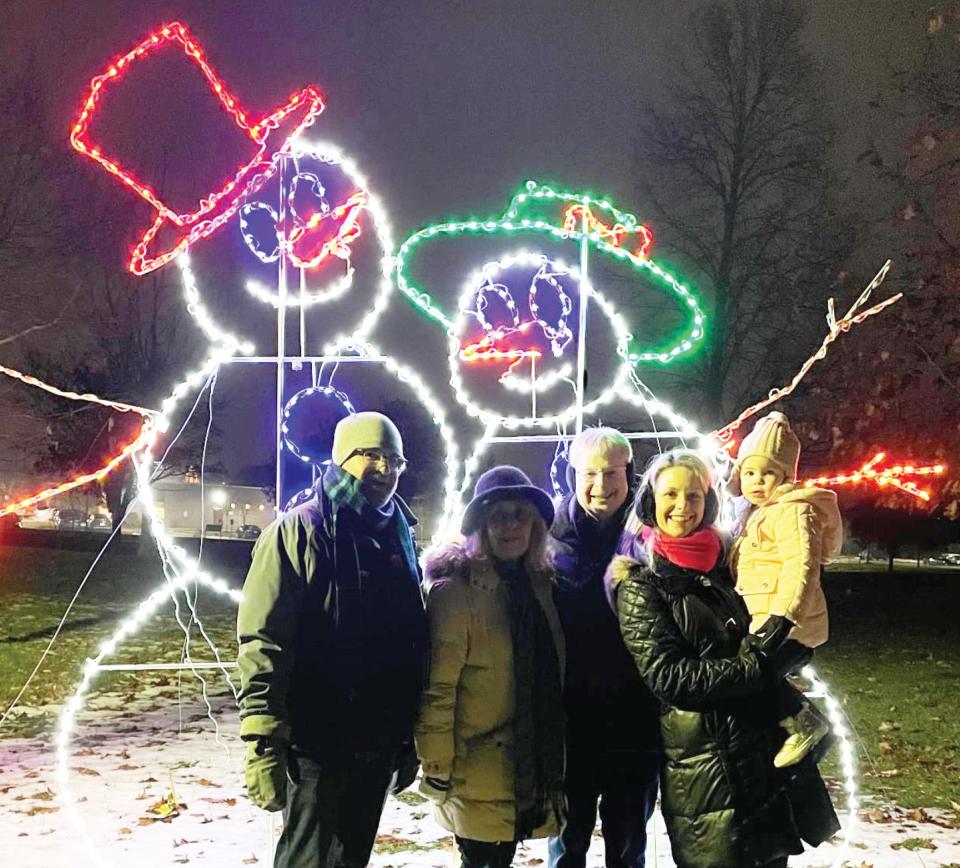 Visitors pose for a photo in front of a seasonal light display during Holidays in Heritage Park in Canton.