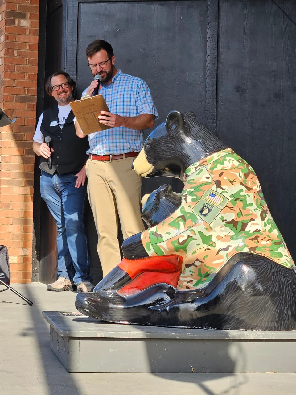 Community Development Director Lew Holloway, right, and emcee Bryan Byrd present the Homecoming Bear at the May 10 Bearfootin' Art Walk in Hendersonville.