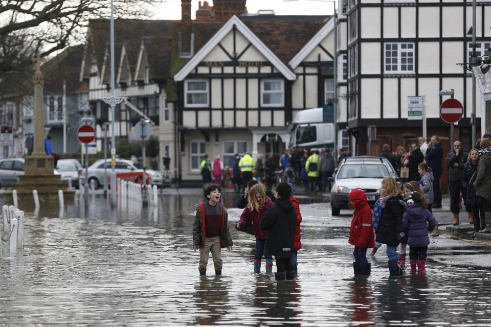 Children react in a flooded street, in Datchet, England, Monday, Feb. 10, 2014. The River Thames has burst its banks after reaching its highest level in years, flooding riverside towns upstream of London. Residents and British troops had piled up sandbags in a bid to protect properties from the latest bout of flooding to hit Britain. But the floods overwhelmed their defences Monday, leaving areas including the centre of the village of Datchet underwater. (AP Photo/Sang Tan)