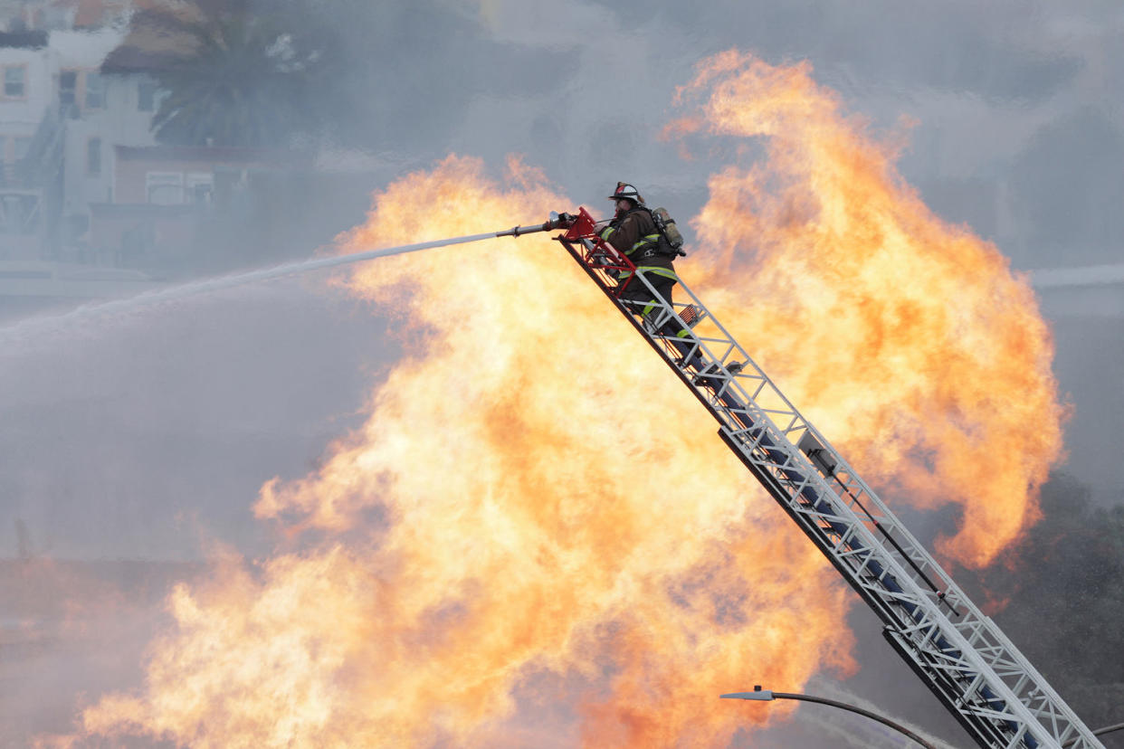 A San Francisco firefighter on a ladder  (Carlos Avila Gonzalez / San Francisco Chronicle via Getty Images)