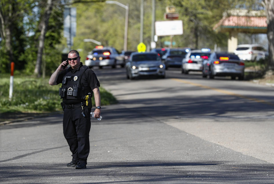 A Knoxville police officer talks on the phone at the scene of a shooting at Austin-East Magnet High School Monday, April 12, 2021, in Knoxville, Tenn. (AP Photo/Wade Payne)