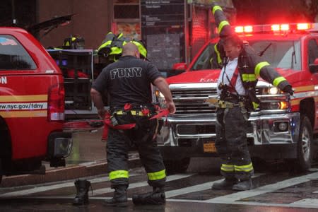 New York City firefighters suit up at the scene after a helicopter crashed atop a building in New York