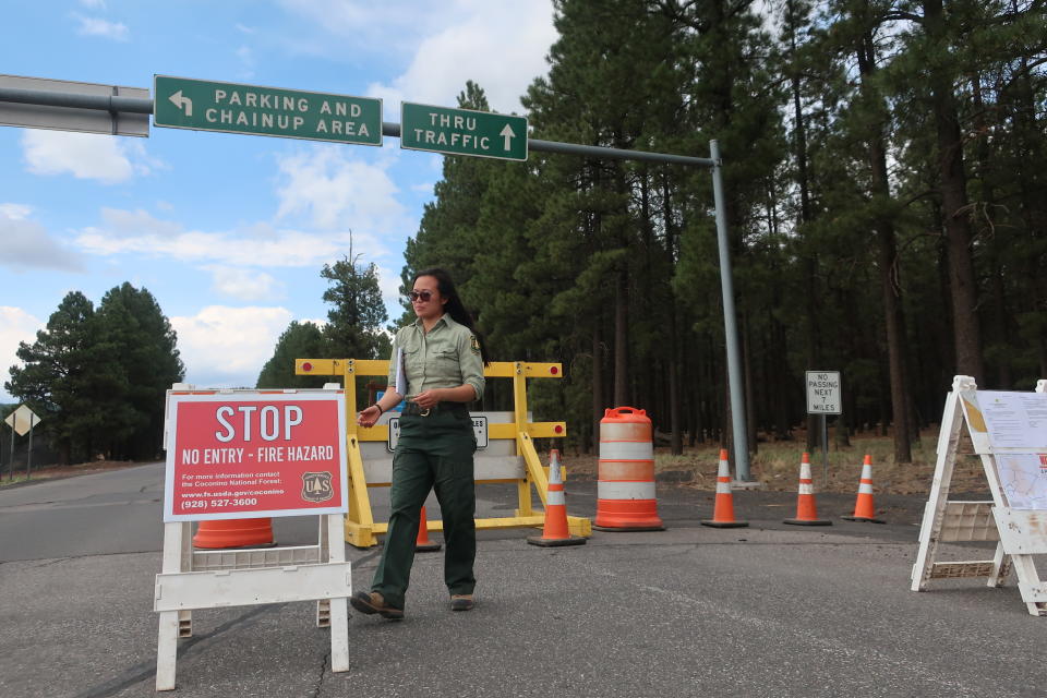 Coconino National Forest employee Amber Wong checks on the road signs outside Flagstaff, Ariz., on Wednesday June 23, 2021. The Coconino National Forest is one of a handful of forests in Arizona that closed this week amid high fire danger as resources are stretched thin with blazes burning across the state. (AP Photo/Felicia Fonseca)