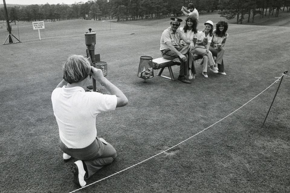 Johnny Miller takes a photograph of a Pinkerton security guard with some fans at the No. 1 tee box.