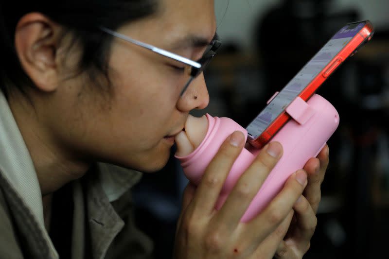 Jing Zhiyuan uses a remote kissing device "Long Lost Touch", as he demonstrates for camera how to use it during an interview with Reuters, at his home in Beijing