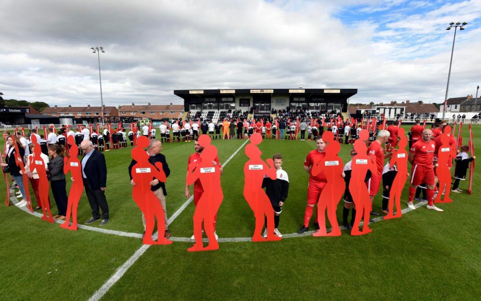 Los jugadores sostienen siluetas que representan a 66 futbolistas que sucumbieron a la demencia antes del Billion Pound Game organizado por Head for Change en Spennymoor Town FC