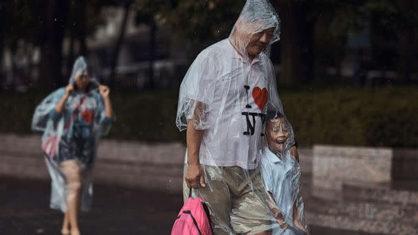 PHOTO: A family walks wearing rain covers, Thursday, July 21, 2022, in New York City. (Andres Kudacki/AP)