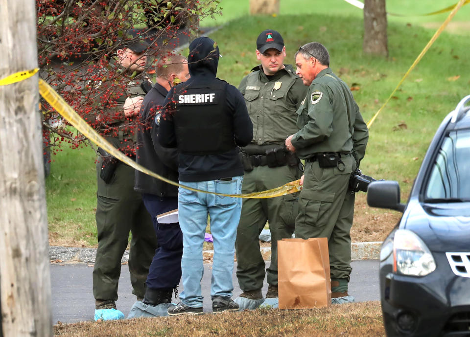 Police stand on Oct. 26, 2023, by the scene with an evidence bag in the parking lot of Schemengees Bar and Grille which was the scene of a mass shooting the night prior in   Lewiston, Maine. / Credit: John Tlumacki/The Boston Globe via Getty Images