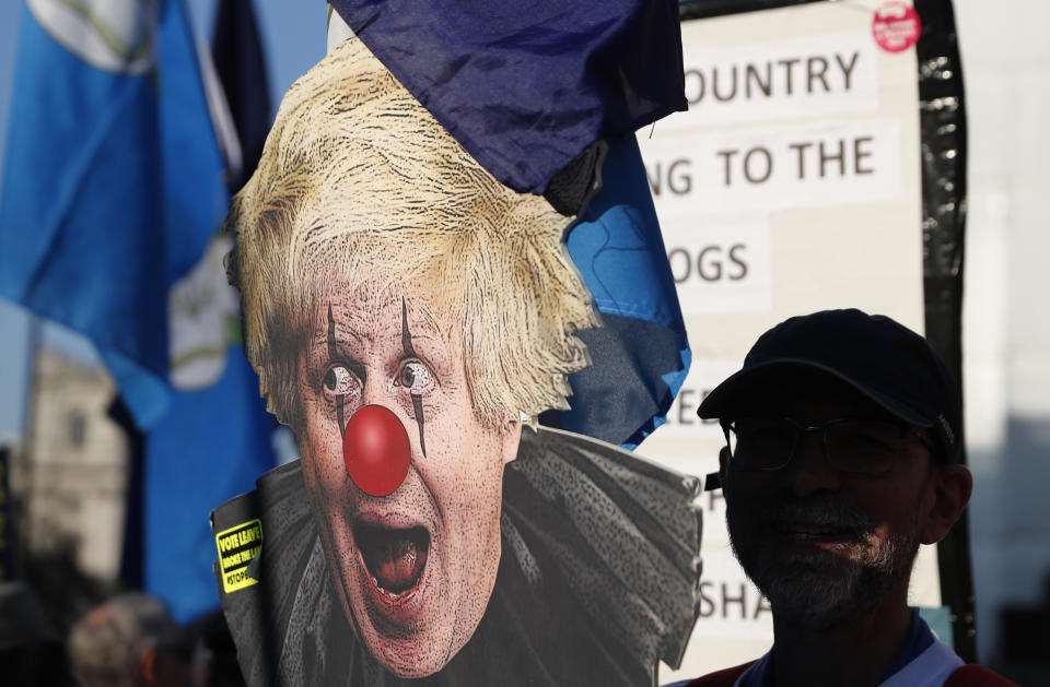 A European Union supporter holds up a placard showing the face of a prominent British lawmaker and leave the EU supporter Boris Johnson, during a demonstration outside the Palace of Westminster in London, Wednesday, Feb. 27, 2019. British Prime Minister Theresa May says she will give British lawmakers a choice of approving her divorce agreement, leaving the EU March 29 without a deal or asking to delay Brexit by up to three months. (AP Photo/Alastair Grant)