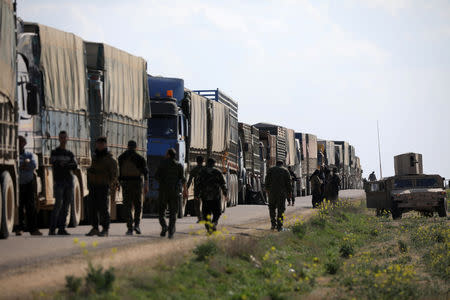 Fighters from Syrian Democratic Forces (SDF) walk near a convoy of trucks near the village of Baghouz, Deir Al Zor province, Syria February 20, 2019. REUTERS/Rodi Said