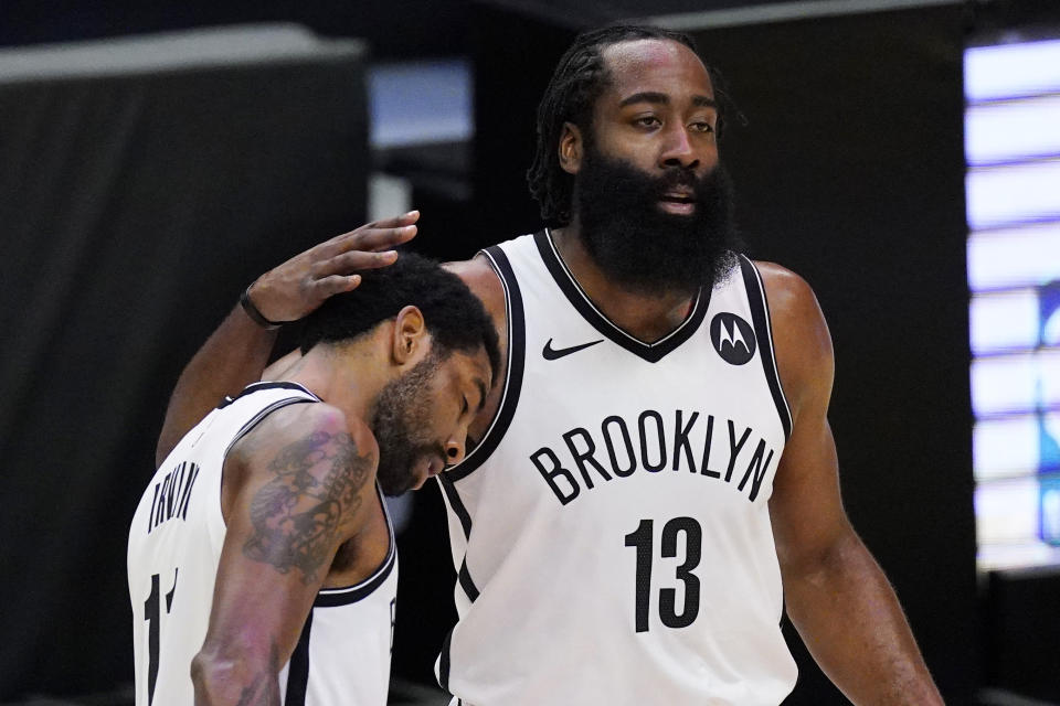 Brooklyn Nets guard Kyrie Irving, left, gets a pat on the head from guard James Harden during a timeout in the first half of the team's NBA basketball game against the Los Angeles Clippers on Sunday, Feb. 21, 2021, in Los Angeles. (AP Photo/Mark J. Terrill)