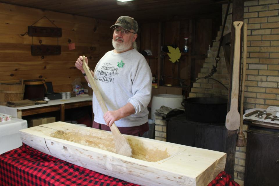 Chuck Dively, who has been making maple sugar cakes in Maple Festival Park since 1982, stands by the new trough he hollowed out from a cucumber magnolia tree in the past few months. The new trough was used for the first time this weekend at the Pennsylvania Maple Festival, which continues Wednesday through Sunday.