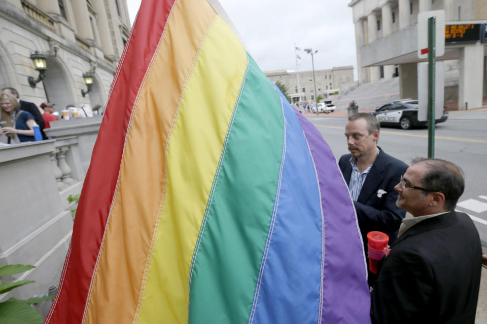 James Porter, right, and his partner Shon DeArmon carry a flag in support of the county issuing marriage licenses for same-sex couples at the Pulaski County Courthouse in Little Rock, Ark., Monday, May 12, 2014. Dozens of gay couples, some of whom waited in line overnight, received licenses to marry from county clerks Monday, while lawyers for the state of Arkansas asked its highest court to suspend an order gutting a constitutional amendment that bans same-sex marriage. (AP Photo/Danny Johnston)