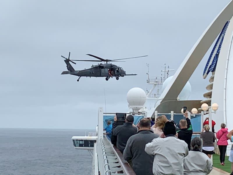 Passengers on board the Grand Princess cruise ship off San Francisco watch while a U.S. military helicopter hovers above the deck